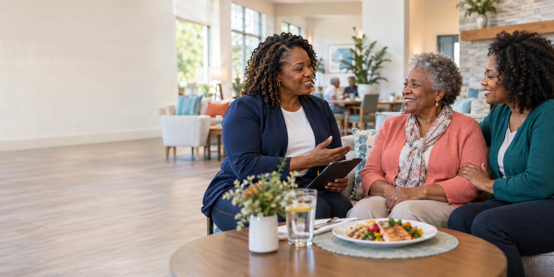 A care navigator speaking with an older woman and her daughter in a welcoming community lounge